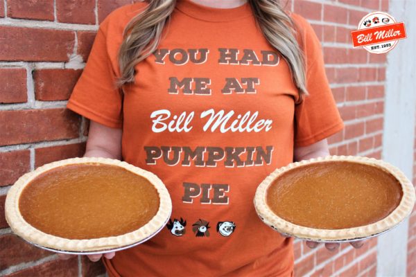 Woman holding two pumpkin pies while wearing a Bill Miller tshirt. Text on tshirt reads, You Had Me At Bill Miller Pumpkin Pie
