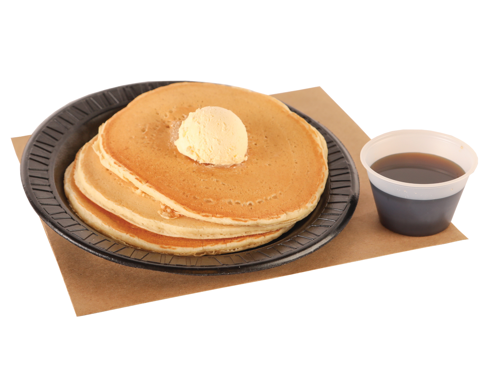 3 griddle cakes with syrup and butter on top on top of brown paper
